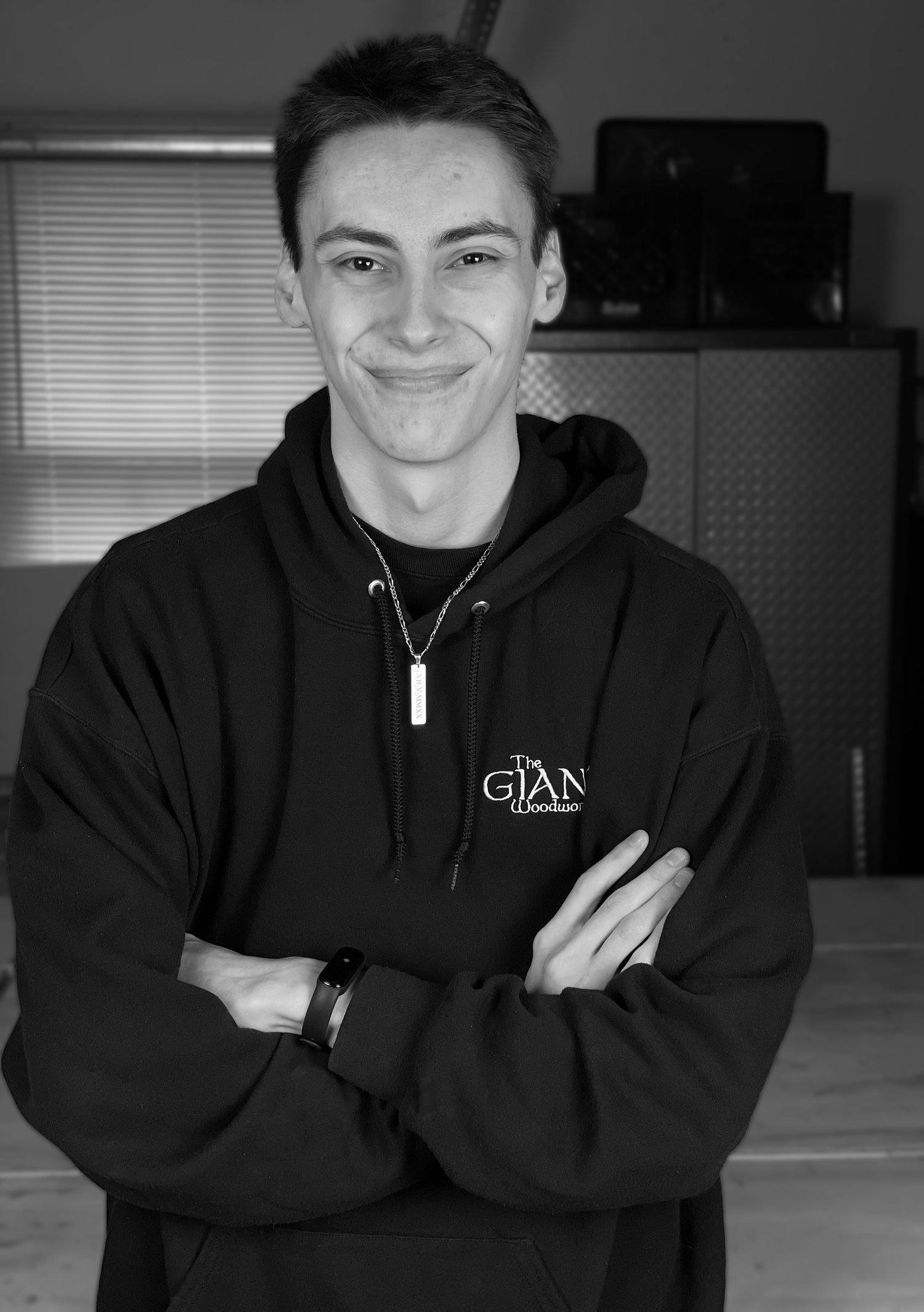 Founder Logan Prichard standing in front of his workshop for a portrait photo in his branded hoodie.